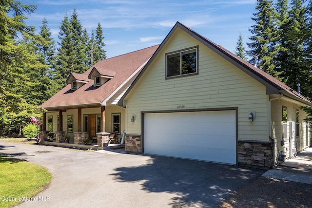 25400 N Lantern Hill Rd, Rathdrum, ID 83858 - view of front of property featuring covered porch, stone siding, asphalt driveway, and a garage