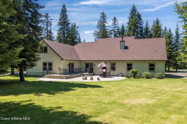25400 N Lantern Hill Rd, Rathdrum, ID 83858 - back of property featuring a patio, a lawn, a deck, and a shingled roof