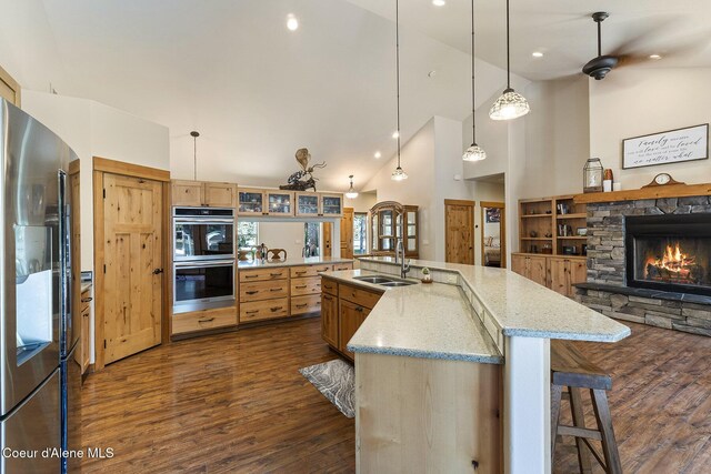 25400 N Lantern Hill Rd, Rathdrum, ID 83858 - kitchen with stainless steel appliances, dark wood-style flooring, a kitchen bar, a stone fireplace, and high vaulted ceiling