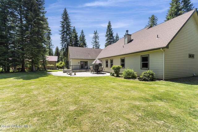 25400 N Lantern Hill Rd, Rathdrum, ID 83858 - back of property with a patio area, a chimney, and a yard