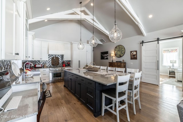 10383 N Morris Rd, Hayden Lake, ID 83835 - kitchen featuring a barn door, stainless steel stove, white cabinetry, dark cabinets, and a kitchen bar