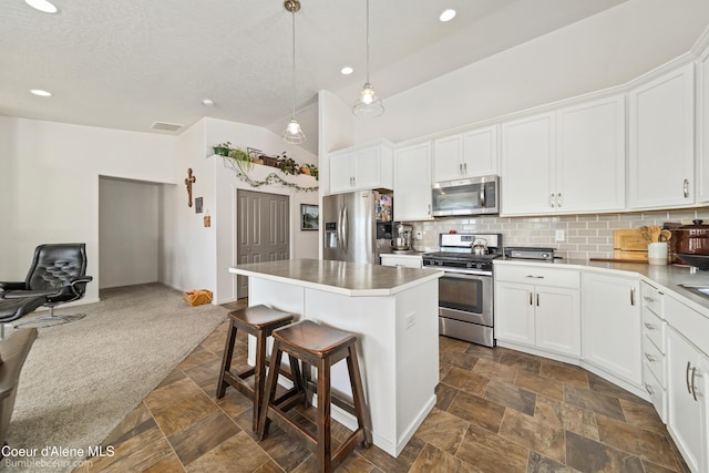 4281 N Shelburne Loop, Post Falls, ID 83854 - kitchen with stainless steel appliances, a kitchen breakfast bar, backsplash, a kitchen island, and white cabinetry