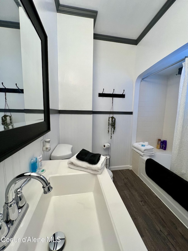 124 King St, Wallace, ID 83873 - bathroom featuring wood finished floors, crown molding, toilet, shower / bath combo with shower curtain, and a sink