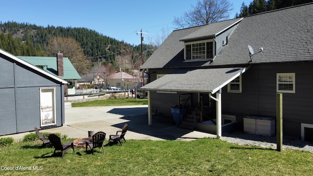 124 King St, Wallace, ID 83873 - rear view of house featuring an outdoor fire pit, a yard, a patio, and a shingled roof