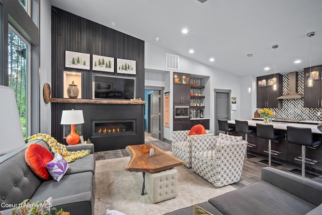 6036 W Sparrowhawk Dr, Rathdrum, ID 83858 - living room featuring recessed lighting, light wood-style flooring, a glass covered fireplace, lofted ceiling, and bar