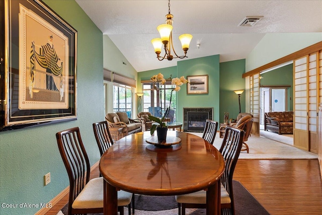 1010 E Mullan Ave Unit 202, Coeur Dalene, ID 83814 - dining room featuring vaulted ceiling, a chandelier, wood finished floors, a glass covered fireplace, and baseboards