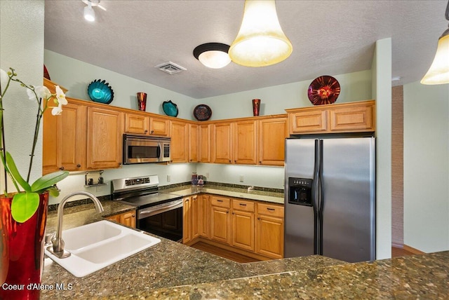 1010 E Mullan Ave Unit 202, Coeur Dalene, ID 83814 - kitchen with stainless steel appliances, a sink, a textured ceiling, pendant lighting, and dark stone counters