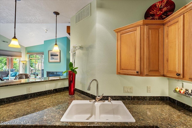 1010 E Mullan Ave Unit 202, Coeur Dalene, ID 83814 - kitchen featuring a sink, hanging light fixtures, brown cabinetry, a textured ceiling, and lofted ceiling