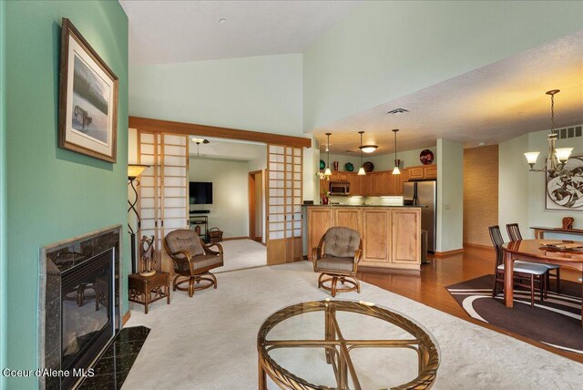 1010 E Mullan Ave Unit 202, Coeur Dalene, ID 83814 - living area featuring a fireplace, a chandelier, baseboards, and high vaulted ceiling