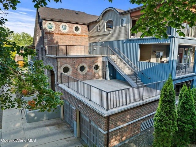 1010 E Mullan Ave Unit 202, Coeur Dalene, ID 83814 - back of property with a balcony, brick siding, stairway, and an attached garage