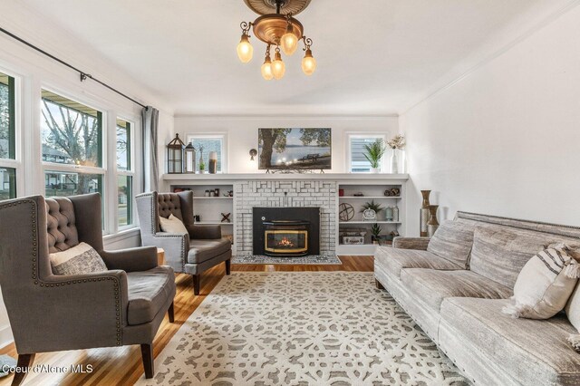 721 N A St, Coeur Dalene, ID 83814 - living area featuring a brick fireplace, wood finished floors, a chandelier, and crown molding