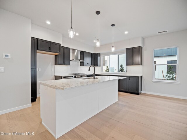 997 E Railroad Ave, Post Falls, ID 83854 - kitchen featuring wall chimney exhaust hood, a sink, light wood-style flooring, light stone counters, and recessed lighting