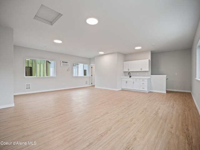 997 E Railroad Ave, Post Falls, ID 83854 - unfurnished living room featuring an AC wall unit, light wood-style floors, baseboards, and recessed lighting