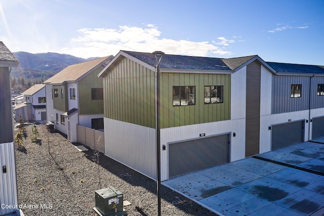997 E Railroad Ave, Post Falls, ID 83854 - view of side of property with an attached garage, a mountain view, a shingled roof, and concrete driveway