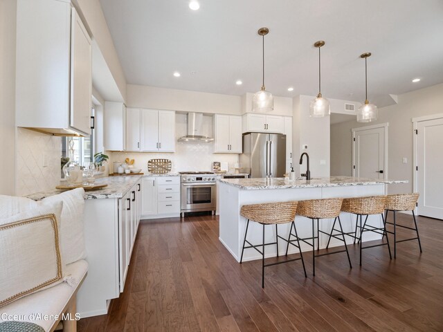 1031 E Railroad Ave, Post Falls, ID 83854 - kitchen featuring wall chimney range hood, appliances with stainless steel finishes, dark wood finished floors, a breakfast bar area, and recessed lighting