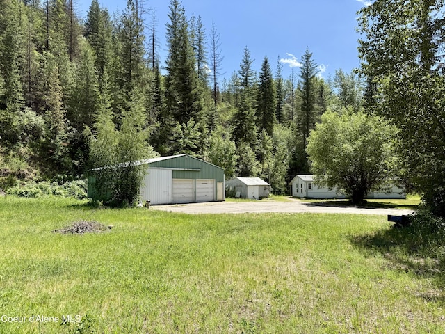 1068 Moon Gulch Rd, Kellogg, ID 83837 - view of green lawn with dirt driveway, a detached garage, and an outdoor structure