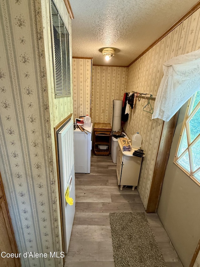1068 Moon Gulch Rd, Kellogg, ID 83837 - kitchen featuring light wood-type flooring, washer / dryer, a textured ceiling, wallpapered walls, and ornamental molding