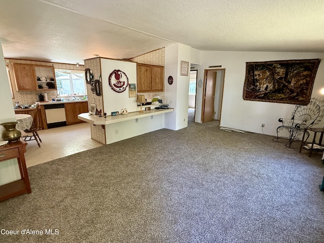 1068 Moon Gulch Rd, Kellogg, ID 83837 - kitchen featuring brown cabinetry, white dishwasher, a textured ceiling, a peninsula, and backsplash