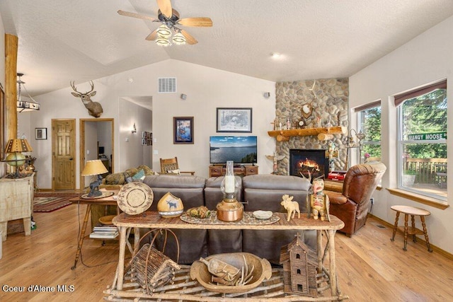 17461 N Right Fork Rd, Hauser, ID 83854 - living room featuring lofted ceiling, light wood finished floors, a stone fireplace, ceiling fan, and a textured ceiling