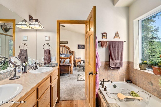 17461 N Right Fork Rd, Hauser, ID 83854 - bathroom with vaulted ceiling, double vanity, a bath, and wood finished floors