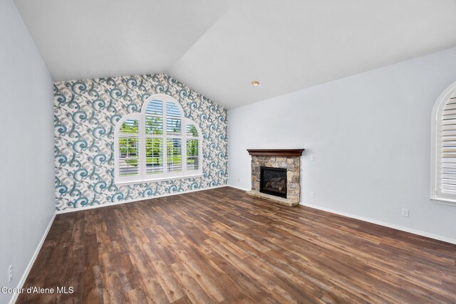 2619 N Tiatan St, Post Falls, ID 83854 - unfurnished living room with wallpapered walls, wood finished floors, vaulted ceiling, baseboards, and a stone fireplace