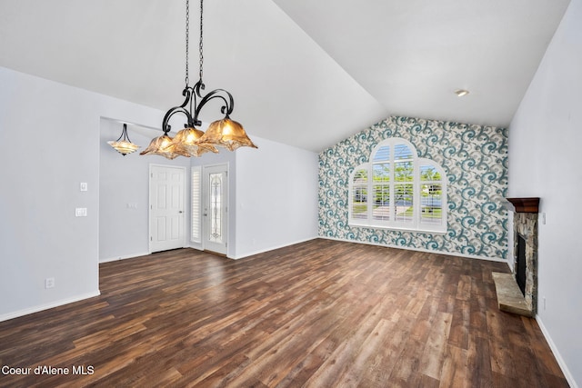 2619 N Tiatan St, Post Falls, ID 83854 - unfurnished living room featuring vaulted ceiling, dark wood-type flooring, wallpapered walls, baseboards, and a stone fireplace