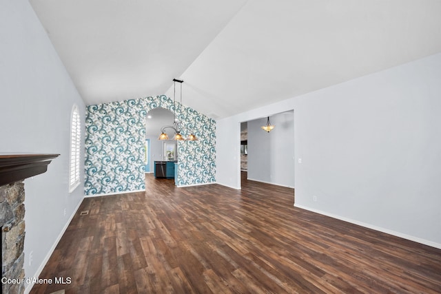 2619 N Tiatan St, Post Falls, ID 83854 - unfurnished living room with wallpapered walls, wood finished floors, vaulted ceiling, baseboards, and a stone fireplace
