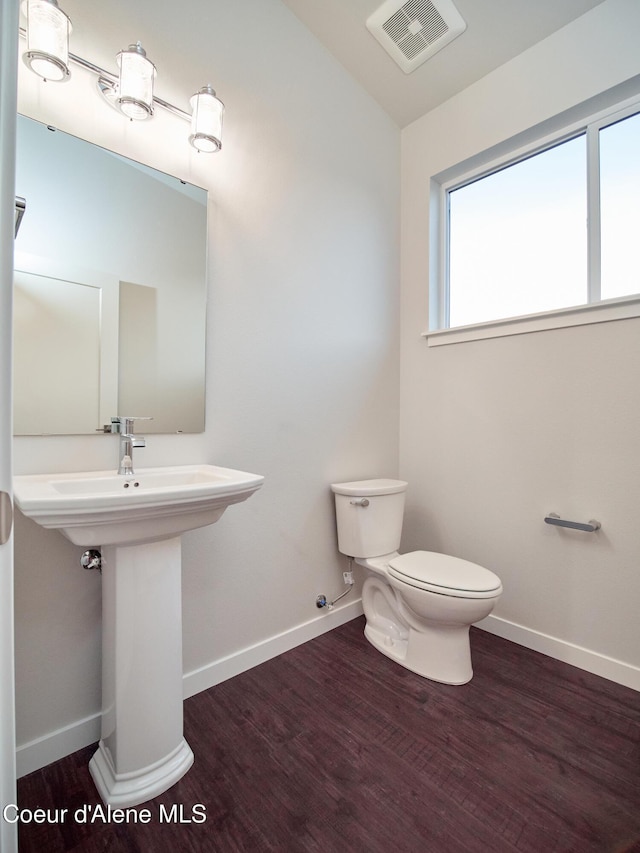 928 E Railroad Ave, Post Falls, ID 83854 - half bathroom featuring toilet, wood finished floors, baseboards, vaulted ceiling, and a sink