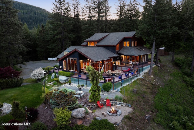 295 Sky Meadow Ln, Sagle, ID 83860 - back of house with a forest view, a fire pit, an outdoor pool, a patio area, and roof with shingles