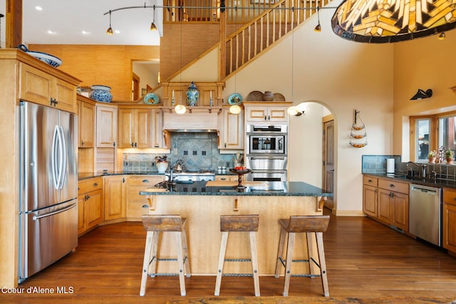 295 Sky Meadow Ln, Sagle, ID 83860 - kitchen featuring stainless steel appliances, a towering ceiling, a sink, backsplash, and arched walkways