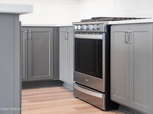 998 E Railroad Ave, Post Falls, ID 83854 - kitchen view of gray cabinetry, stainless steel gas range oven, light wood-style floors, light countertops, and tasteful backsplash