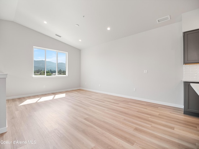 998 E Railroad Ave, Post Falls, ID 83854 - unfurnished living room with lofted ceiling, light wood finished floors, recessed lighting, baseboards, and a mountain view