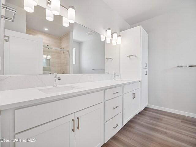 998 E Railroad Ave, Post Falls, ID 83854 - bathroom featuring double vanity, baseboards, a stall shower, and wood finished floors