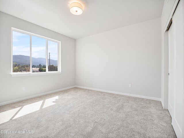 998 E Railroad Ave, Post Falls, ID 83854 - unfurnished bedroom with carpet floors, a closet, a mountain view, and baseboards