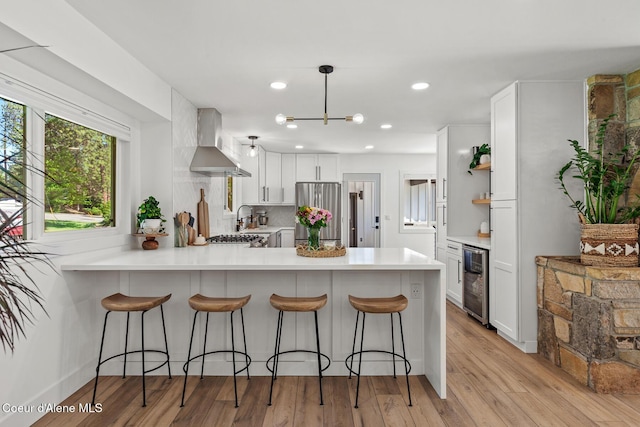 1113 N Lambert Ln, Coeur Dalene, ID 83814 - kitchen featuring wall chimney exhaust hood, freestanding refrigerator, beverage cooler, a peninsula, and white cabinetry