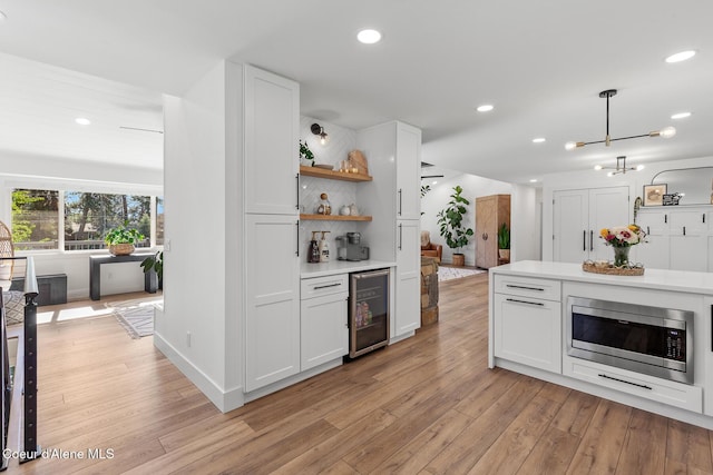 1113 N Lambert Ln, Coeur Dalene, ID 83814 - kitchen with beverage cooler, stainless steel microwave, white cabinetry, open shelves, and light wood finished floors