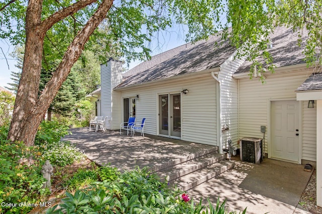 8511 N Summerfield Loop, Hayden, ID 83835 - back of property featuring a chimney, roof with shingles, central AC, and a patio