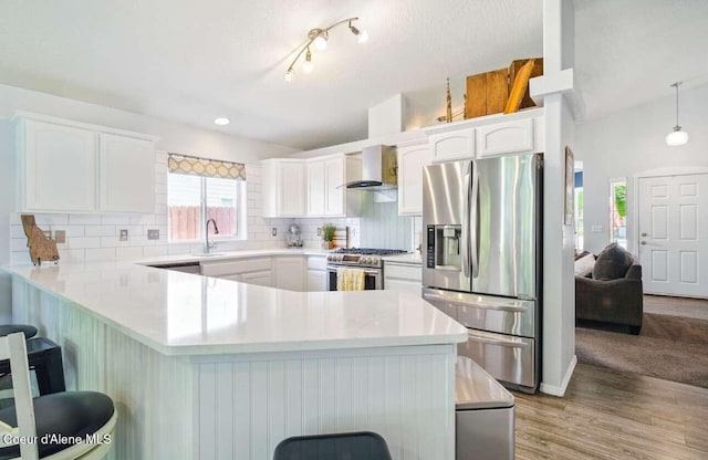 5820 E Steamboat Bnd, Post Falls, ID 83854 - kitchen featuring stainless steel appliances, a peninsula, white cabinets, a kitchen breakfast bar, and decorative backsplash