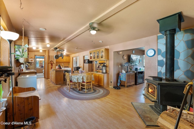 490 Samuels Rd, Sandpoint, ID 83864 - dining area featuring a wood stove, light wood-type flooring, a ceiling fan, and beamed ceiling