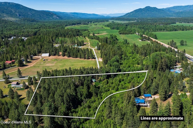 490 Samuels Rd, Sandpoint, ID 83864 - aerial view of sparsely populated area with a heavily wooded area, property parcel outlined, and a mountainous background