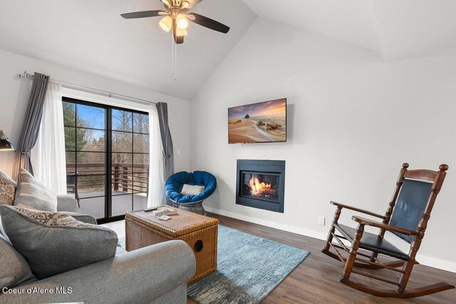 228 Snowgoose Ln Unit 8, Sandpoint, ID 83864 - living area featuring a glass covered fireplace, wood finished floors, a ceiling fan, baseboards, and high vaulted ceiling