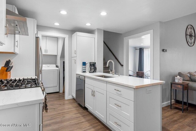 228 Snowgoose Ln Unit 8, Sandpoint, ID 83864 - kitchen with washer / dryer, a sink, stainless steel appliances, wall chimney exhaust hood, and a peninsula