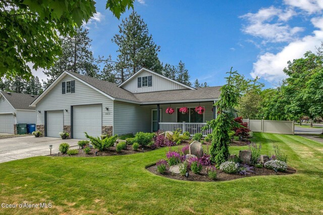 5835 E Steamboat Bnd, Post Falls, ID 83854 - view of front of house featuring covered porch, a garage, driveway, board and batten siding, and stone siding
