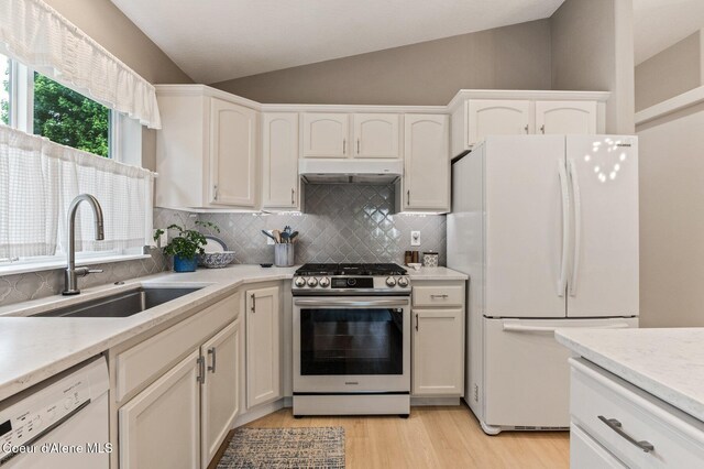 5835 E Steamboat Bnd, Post Falls, ID 83854 - kitchen featuring white appliances, vaulted ceiling, a sink, under cabinet range hood, and backsplash