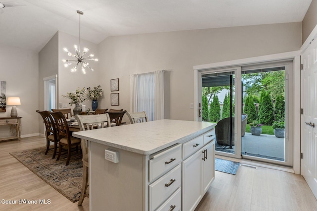 5835 E Steamboat Bnd, Post Falls, ID 83854 - kitchen with a center island, light wood finished floors, a kitchen bar, a chandelier, and white cabinets