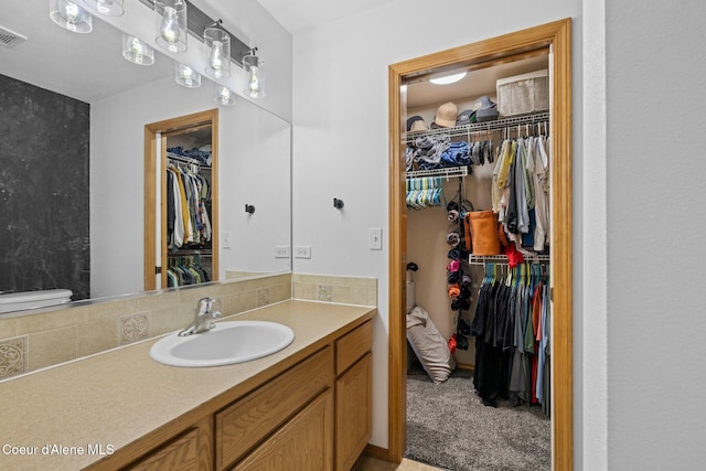 688 N Sparklewood Ct, Post Falls, ID 83854 - bathroom featuring a walk in closet, vanity, and backsplash