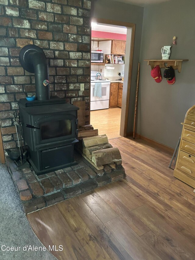 344 N 20th St, Saint Maries, ID 83861 - detailed view of electric stove, stainless steel microwave, a wood stove, wood finished floors, and baseboards