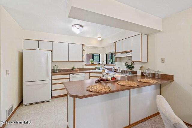 1130 E Timber Ln # 2, Coeur Dalene, ID 83815 - kitchen with white appliances, a peninsula, dark countertops, under cabinet range hood, and a sink