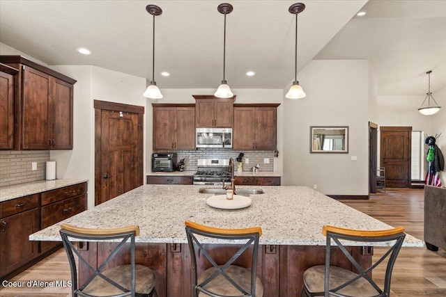 23378 N Prominence Rd, Rathdrum, ID 83858 - kitchen featuring stainless steel appliances, backsplash, light wood-type flooring, a breakfast bar area, and recessed lighting