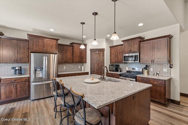 23378 N Prominence Rd, Rathdrum, ID 83858 - kitchen with stainless steel appliances, decorative backsplash, light wood finished floors, a breakfast bar area, and recessed lighting